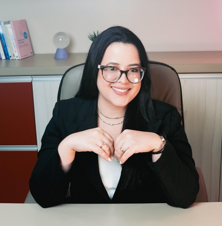 Mônica Mariane sentada à mesa de seu consultório